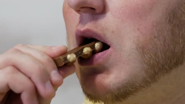 一个年轻人吃带有坚果的开胃巧克力 吃特写牛奶巧克力 — 图库视频影像