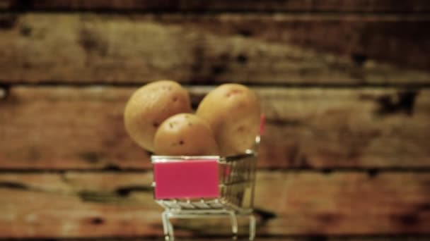 古いボード 自然のジャガイモスタジオの撮影を背景に ロータリーテーブルの上に自分の肌にジャガイモのスライドカメラ 車輪付きスーパーマーケットのカートのジャガイモ — ストック動画