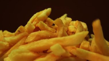 Yakın plan iştah açıcı kızarmış patates kızartması siyah bir arka planda döner tablada. Fast food tuzlu patates. Kızarmış patates dökülüyor.