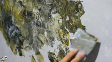 İç taraftaki duvarın dekoratif bir resmini yapan kız, duvarı akrilik boyalı bir spatulayla boyuyor.