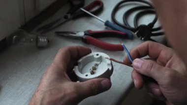 Elektrikçi ustası elektrik lambası için kabloları prize bağlıyor. Elektrik tasarrufu kavramı