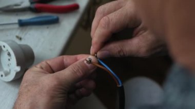 Elektrikçi elektrik kablolarını bağlar. Elektriği kabloya bağlıyorum. Bir adam elektrikçileri bağlamak için vidalara kablo bağlar.