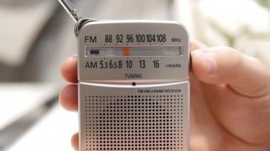 Bir adam radyoda bir radyo dalgasını ayarlıyor. - Evet. Anteni olan antika alıcı. Bir ölçekte analog radyo ayarla. Bir adam eski bir radyodan haberleri dinler.