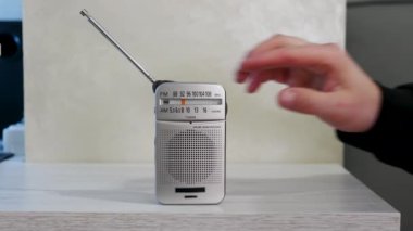 Bir adamın eli eski bir ahşap masadaki radyo dalgasını akort eder. Anteni olan antika alıcı. Nostalji yaşam tarzı. Bir ölçekte analog radyo ayarla. Bir adam eski bir radyodan haberleri dinler. müzik dinliyordum..