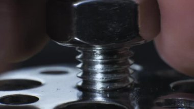 Bir adam vida somunu sıkıyor. Endüstriyel çelik. Fındık makrolu cıvata.