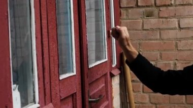 Yaşlı bir adamın eli eski bir evdeki eski bir kapıyı çalar, bir ziyaretçi ahşap kapıyı çalar. Dışarıdaki eski bir eve ağır çekim vuruyor..