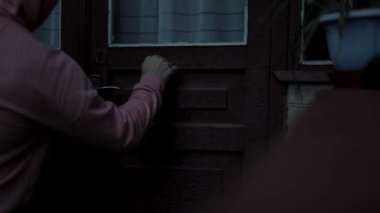 Kapüşonlu bir adam eski bir evin eski kapısını çalıyor, bir tür horor. Genç bir adam eski bir eve ziyaretçidir. Bir adamın eli ağır çekimde tuğladan bir evin ahşap kapısını çalar..