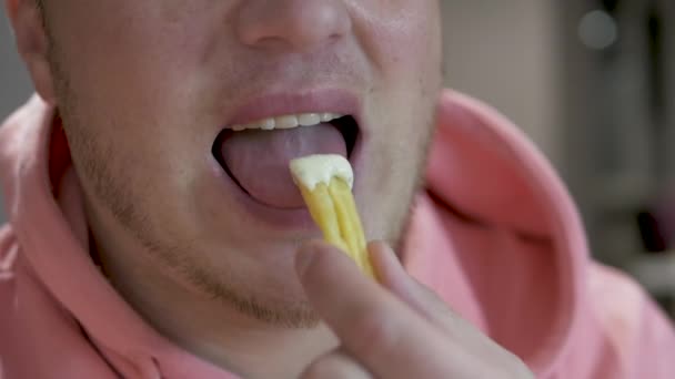 フランス語 不健康な食品を食べる若い男のスローモーションのクローズアップ ピンクのパーカーを着た男がポテトフライを食べて噛んだ カフェでのファーストフード人が食べる — ストック動画
