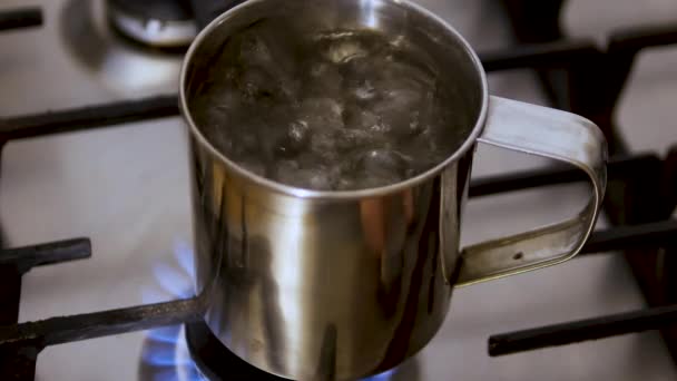 クローズアップ金属製の観光カップで沸騰水 沸騰したお湯でお茶を淹れる お湯のカップにティーバッグを浸します ガスを使ったウクライナの電力不足 — ストック動画
