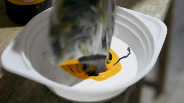 アクリル絵具をボウルにへらで混ぜます 室内での絵画 作家は黒と黄色の塗料を混ぜ合わせる — ストック動画