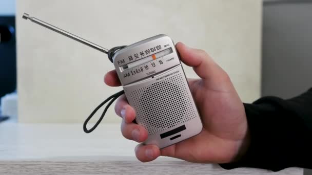 拿着收音机 把收音机里的无线电波调到一张旧的木制桌子上 带有天线的古董接收机 怀旧的生活方式按比例调模拟收音机 一个人在旧收音机里听新闻 听音乐 — 图库视频影像