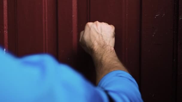 若い男が古い村のドアをノックし 訪問者はバーガンディの木製のドアをノックします 外の古い家でゆっくりとした動き — ストック動画
