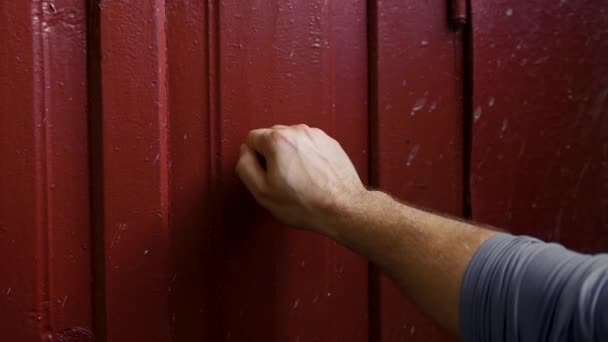 若い男の手は古い村のドアをノックし 訪問者はバーガンディの木製のドアをノックします 古い家の中でゆっくりとした動き — ストック動画