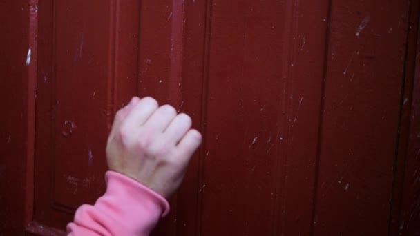 Mão Jovem Com Uma Manga Rosa Bate Uma Porta Vermelha — Vídeo de Stock