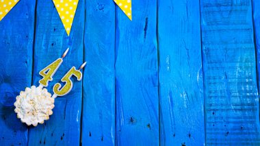 Üst görünüm arka plan şenliği turta ve dekorasyonlu klasik mavi panolar üzerine. Geçmişini tebrik ederim. 45 numaralı mumdan bir numarayla doğum günün kutlu olsun..