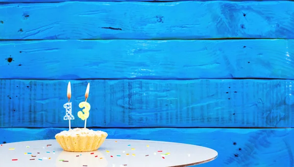 Festive background with a cake on the background of blue boards, copy space, a beautiful background for a birthday with a number a candle with a figure 13