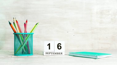 16 Eylül takvimi. Sezonun buluşması konsepti. Defterin arka planına ve ayın tarihine karşı sepetteki kalemler. Boşluk takvim küpünü kopyala