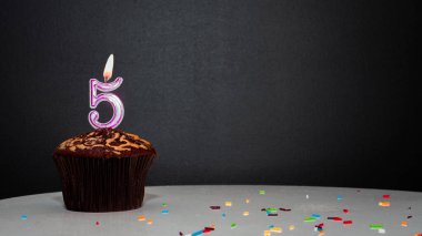 Siyah üzerine muffin ve 5 numaralı mumdan bir numara. Kopyalama alanı, siyah arkaplanda bir turta, doğum gününü kutlamak için bir kart, yıldönümü