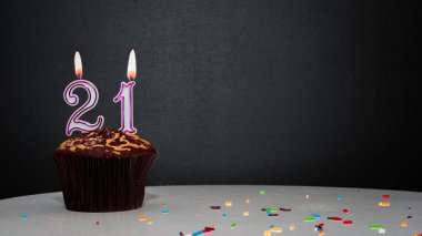 Siyah üzerine muffin ve 21 numaralı mumdan bir numara. Kopyalama alanı, siyah arkaplanda bir turta, doğum gününü kutlamak için bir kart, yıldönümü
