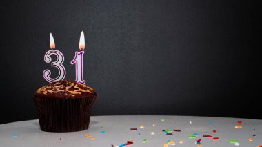 Siyah üzerine muffin ve 31 numaralı mumdan bir numara. Kopyalama alanı, siyah arkaplanda bir turta, doğum gününü kutlamak için bir kart, yıldönümü