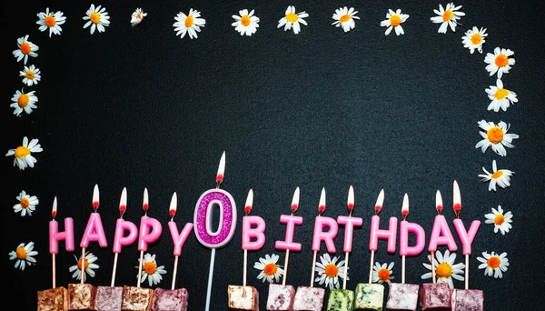 Happy birthday background with number 0. Copy space. Pink happy birthday candles on a black background. Happy birthday flower frame