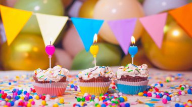 Balonların arka planında mum olan kremalı çok renkli kekler, mutlu yıllar şenlik arka planı. Tatil için süslemeler.