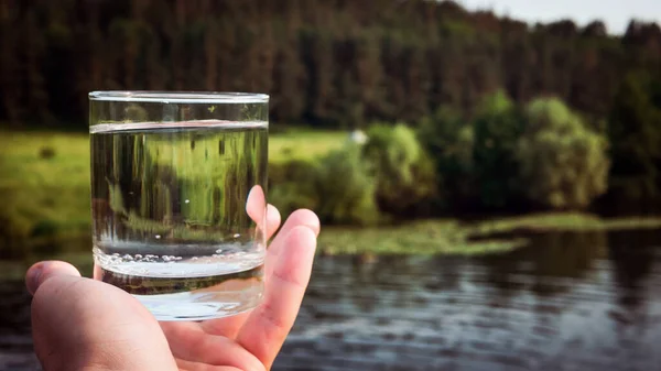 A glass of drinking water on a mountain slope, mineral water with bubbles on the background of nature