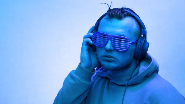 Portrait of a man in headphones, music background, neon man in yellow colors happy in headphones listens to music and in club glasses. Copy space