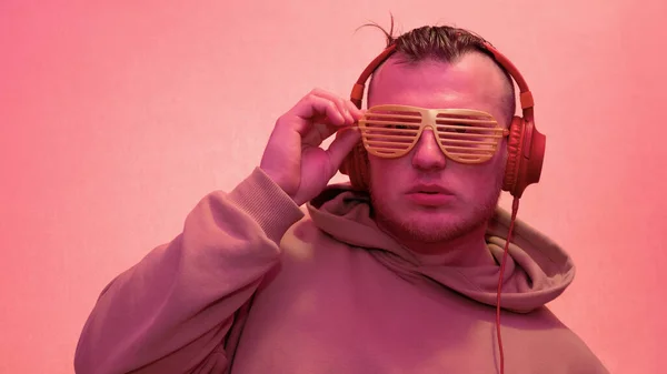 Portrait of a man in headphones, music background, neon man in yellow colors happy in headphones listens to music and in club glasses. Copy space