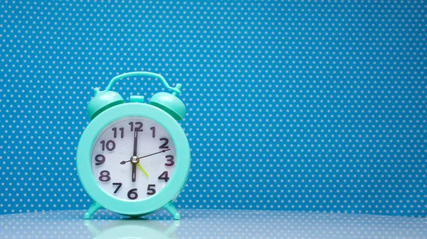 Retro alarm clock on the hands of the clock 6 am copy space. Clock display on a blue background