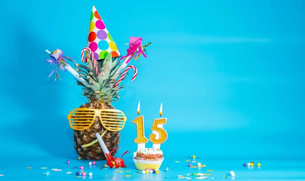 Creative congratulations on the fifteenth birthday for a child. Pineapple with glasses in festive decorations. copy space. 15 year old birthday. Merry fruit birthday card