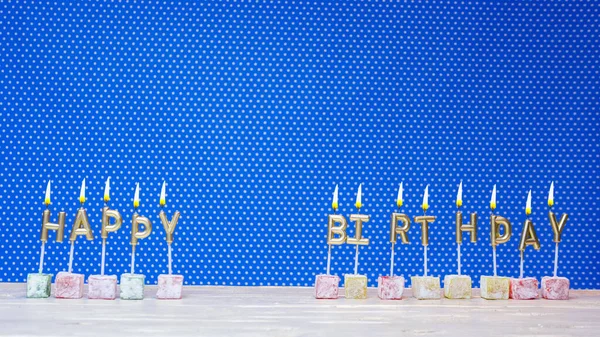 Happy birthday card from letters of candles on a blue background with polka dots white copy space. Happy birthday for any age