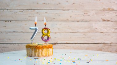 Beyaz panolardaki gümüş numaralardan 78 yıl boyunca mutlu yıllar. Güzel bir doğum günü kartı ve 78 yıl boyunca yanan mumlu bir kek.