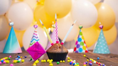 Çok renkli toplar ve şapkaların arka planında mumlar olan neşeli kek, mutlu yıllar. Kekli pembe hediye kutusu..