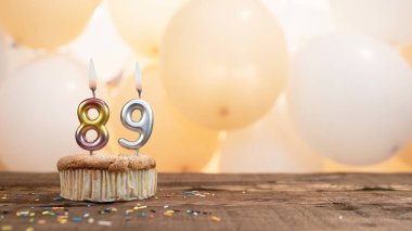 89 numaralı mumlu doğum günü kartı balonların arka planındaki kekin içinde. Kopyalama uzayı 89 yıllık doğum günün kutlu olsun.
