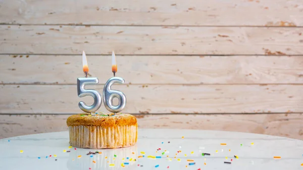 ホワイトボードのコピースペースを背景に銀の数字から56年のための幸せな誕生日の挨拶 56年のための燃えるろうそくとマフィンと美しい誕生日カード — ストック写真
