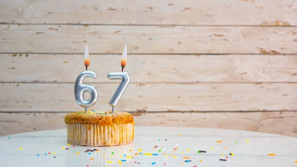 白い板の背景のコピースペースの銀数からの幸せな67歳の誕生日の挨拶 67年もの間 キャンドルが灯されたカップケーキ付きの美しい誕生日カード — ストック写真
