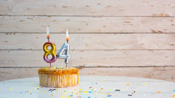 ホワイトボードの背景コピースペース上の銀の数字から幸せな84誕生日の挨拶 84年もの間 キャンドルが灯されたカップケーキ付きの美しい誕生日カード — ストック写真