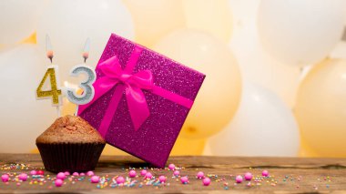 43 yaşındaki bir kadın için pembe hediye kutusuyla mutlu yıllar. Güzel bir doğum günü kartı, içinde kek ve yanan 43 numaralı mum var.