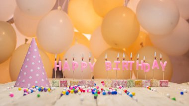 Her yaş için yanan mumlar, doğum günü mumları pembe mektuplar. Balonlu şenlikli arkaplan.