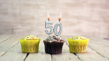 Happy birthday muffins with candles with the number 50. Card copy space with pies for congratulations