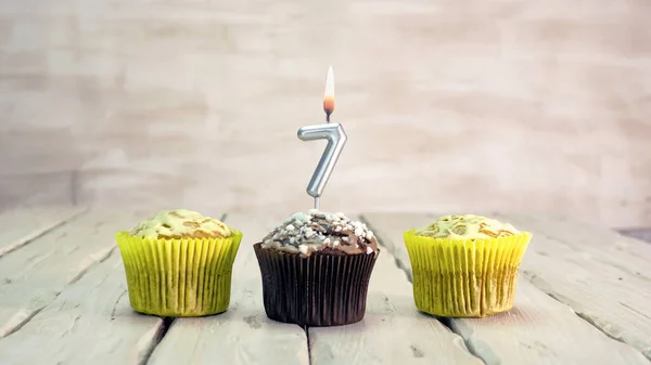 Happy birthday muffins with candles with the number 7. Card copy space with pies for congratulations