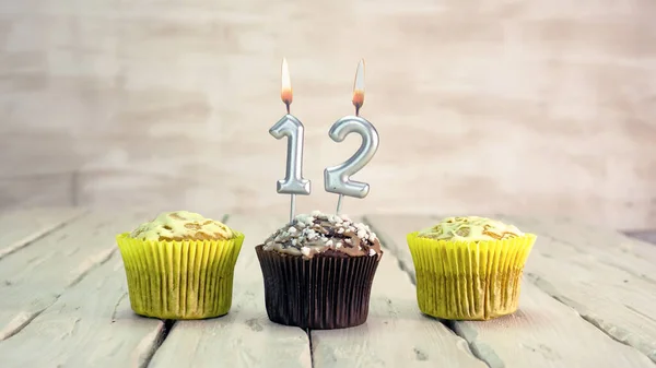 Happy birthday muffins with candles with the number 12. Card copy space with pies for congratulations