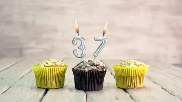 Happy birthday muffins with candles with the number 37. Card copy space with pies for congratulations.