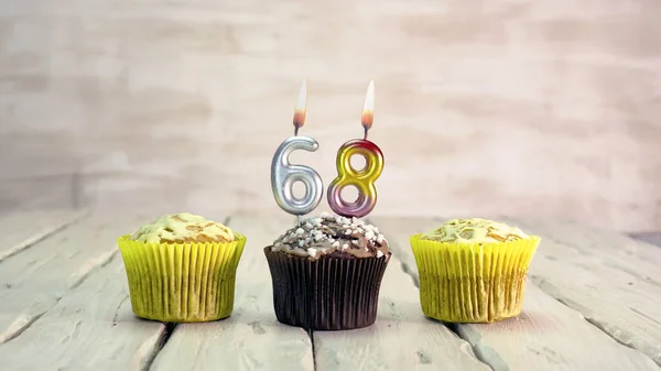 Happy birthday muffins with candles with the number 68. Card copy space with pies for congratulations