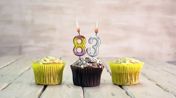 Happy birthday muffins with candles with the number 83. Card copy space with pies for congratulations.