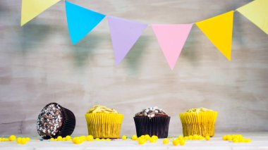 Festive table with multicolored muffins, birthday copy space decorations