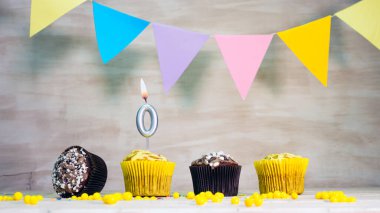 Birthday background with number 0. Beautiful birthday card with colorful garlands, a muffin with a candle burning copyspace