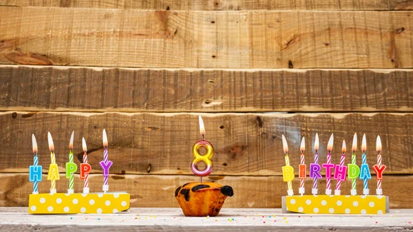 Muffin with a burning candle background for the anniversary on a beautiful wooden background. Postcard with letters of candles with congratulations for the holiday before the birthday. . Copy space. Happy birthday background 30.
