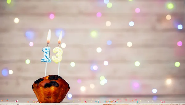 stock image Happy birthday background with muffin and number of candles on light bulbs bokeh background. Greeting card happy birthday copy space with number 13